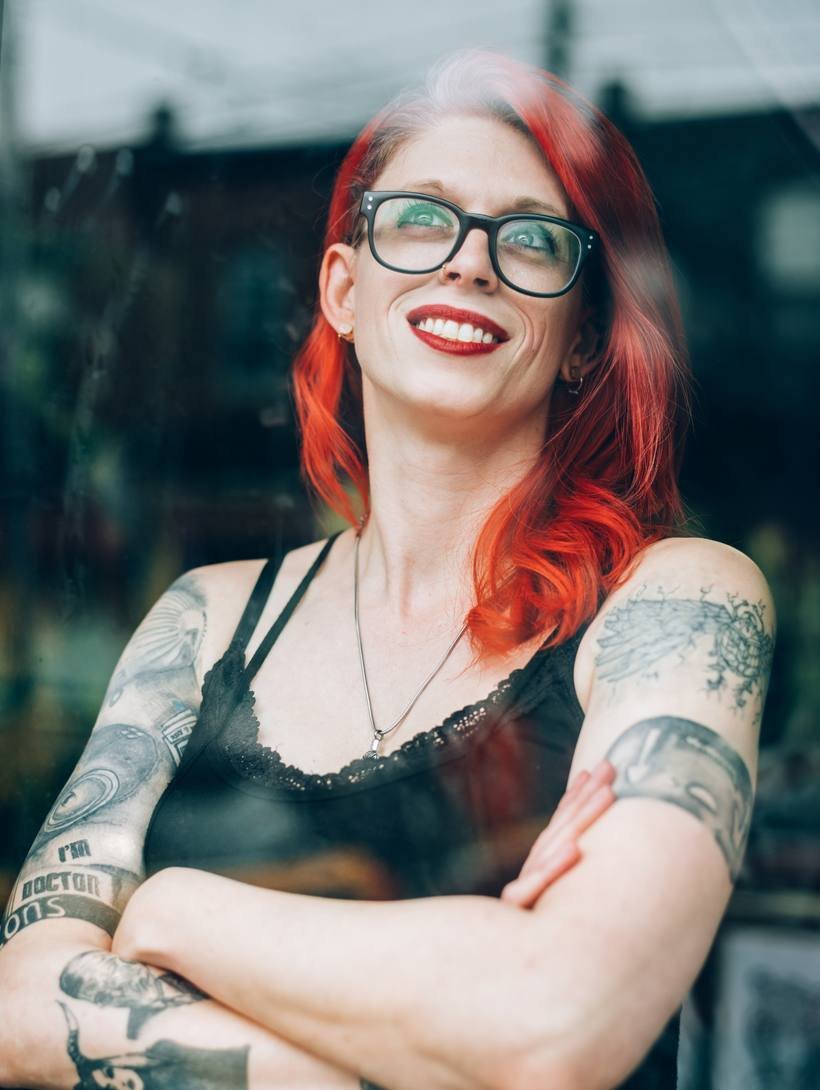 Portret van de artiest van Tattoo Studio X met getatoeëerde armen voor het studioraam