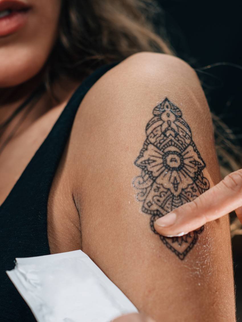 Fijnlijnige mandala-tattoo in zwarte inkt op een bovenarm