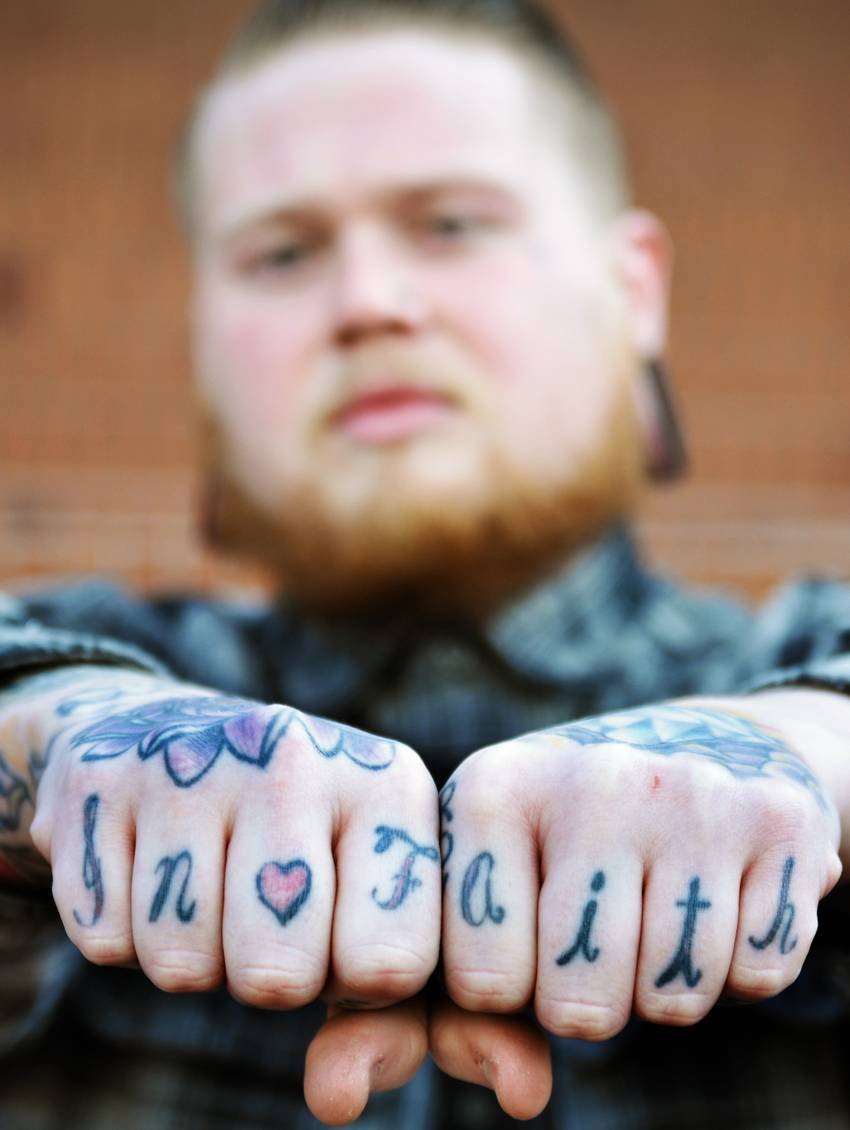 Handen met de letters van het woord faith over de knokkels getatoeëerd