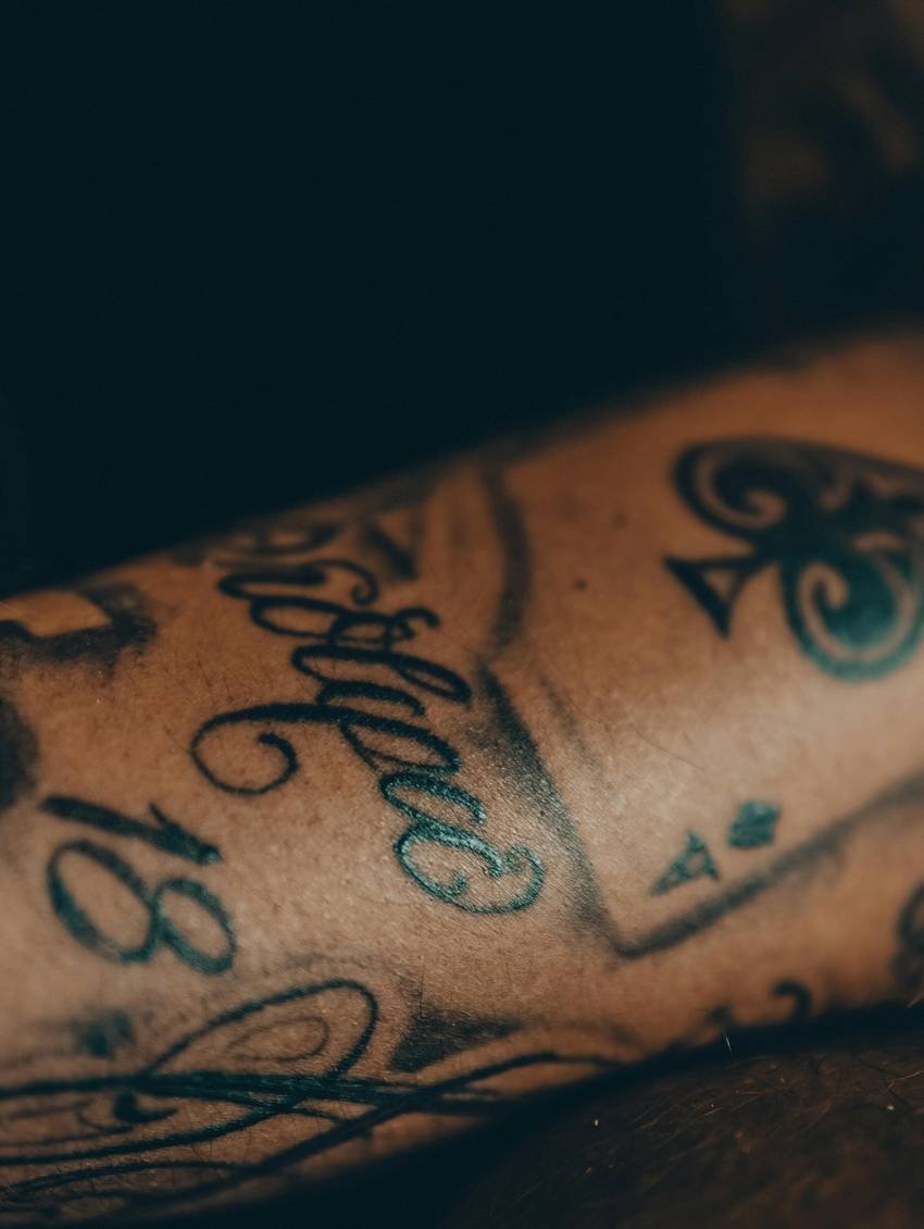 Sierlijk handschrift en symbolen op een onderarm in laag licht